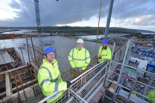 Celebrating reaching the highpoint in the construction of the five-storey apartment building at North Quay, in Hayle, are Corinthian Homes construction director David Speight (centre) with (left) architect Rob Hebblethwaite, of FCB Studios, and Richard Sc